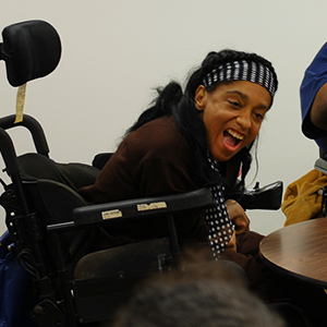 Woman in a power wheelchair leaning forward and laughing