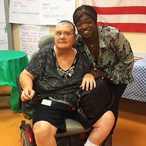 Two people, one in a wheelchair and one crouching, pose for a photo