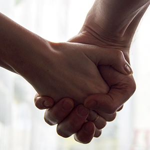 Two people's hands clasped together