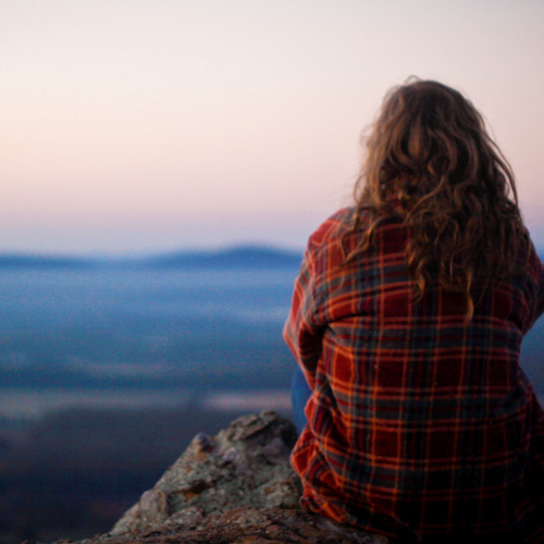 Person sitting on a rock looking out over a landscape