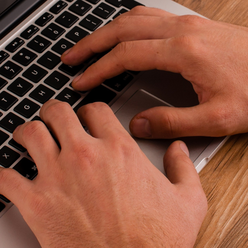 Hands typing on a laptop