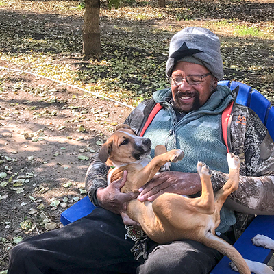 Man rubbing the belly of a puppy in his lap